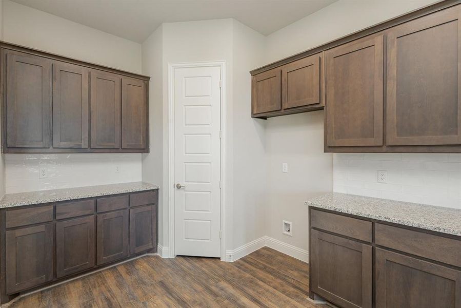 Kitchen with dark hardwood / wood-style flooring, light stone counters, and tasteful backsplash