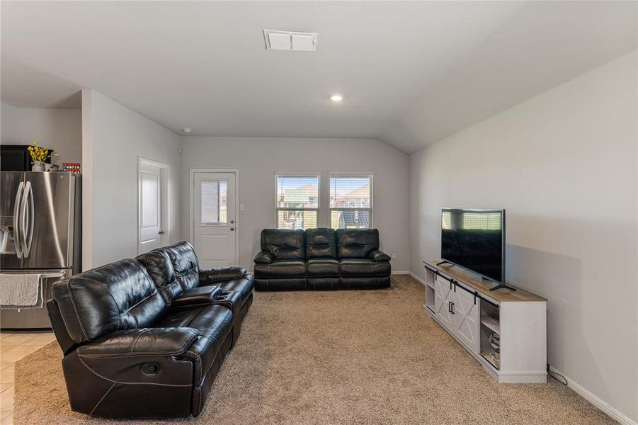 Carpeted living room featuring lofted ceiling