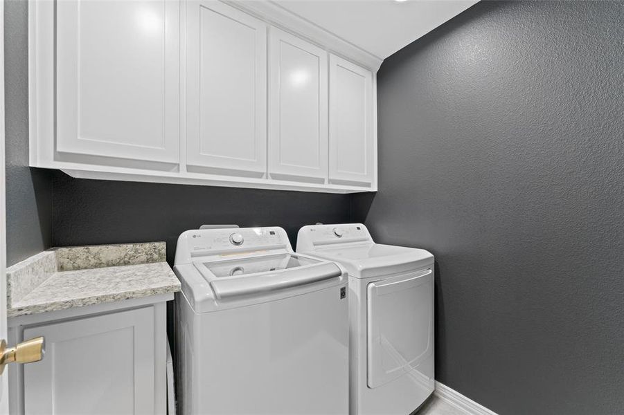 Laundry area featuring washing machine and dryer and cabinets