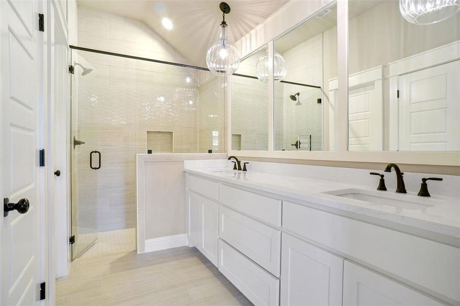 Bathroom with double vanity, tile patterned floors, and a shower with door