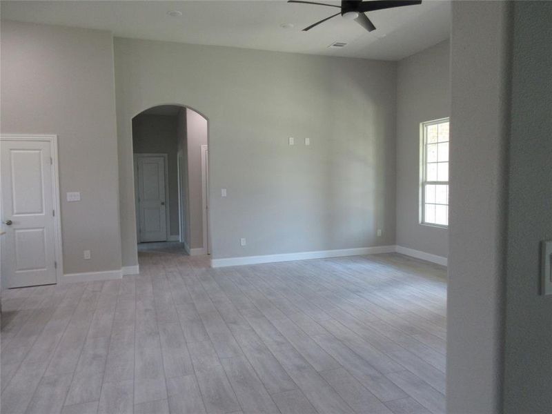 Spare room featuring light hardwood / wood-style flooring, ceiling fan, and a towering ceiling