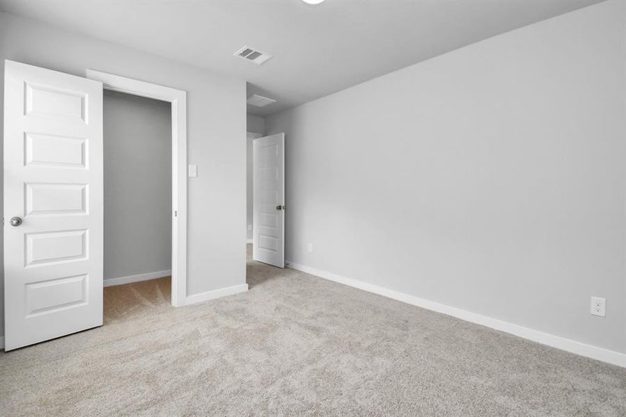 Secondary bedroom features plush carpeting, large windows that let in plenty of natural light, bright paint, and spacious closets. Sample photo of completed home with similar floor plan. Actual colors and selections may vary.