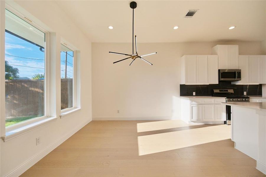 Kitchen featuring backsplash, white cabinetry, range, and a healthy amount of sunlight