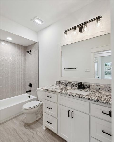 Full bathroom featuring vanity, tiled shower / bath, tile patterned flooring, and toilet