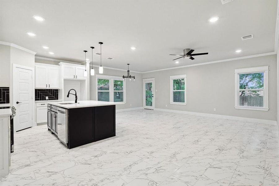 Kitchen with a wealth of natural light, a kitchen island with sink, pendant lighting, sink, and light tile floors