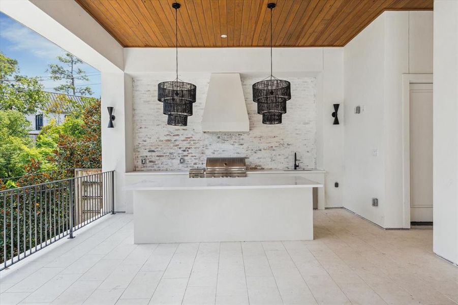 This luxury summer kitchen is designed for ultimate convenience, making it ideal for catering or entertaining with your personal chef. A stunning brick accent wall ties the exterior together beautifully, while dual designer light fixtures add an elegant touch to the space.