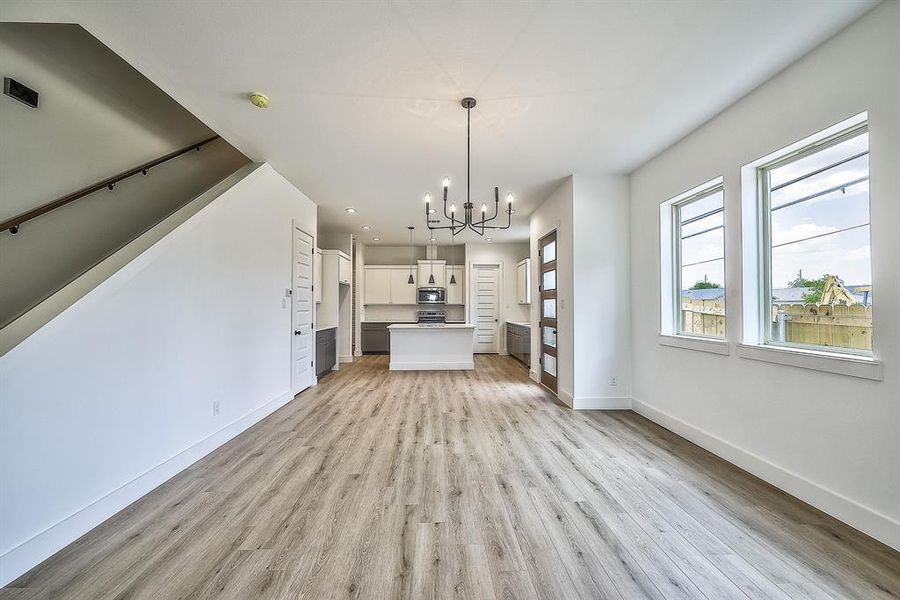 Unfurnished living room with light wood-type flooring and a notable chandelier