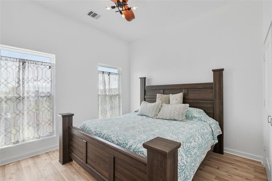 This is the primary bedroom with two windows allowing for plenty of natural light. and a clean modern look with neutral wall colors.