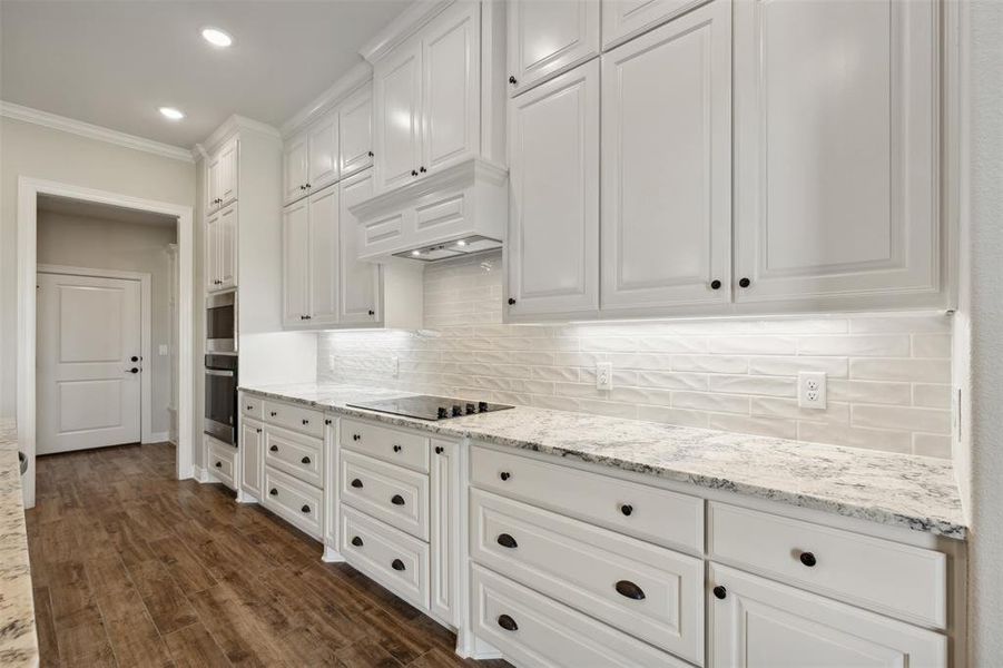 Kitchen featuring backsplash, white cabinetry, black electric cooktop, crown molding, and dark hardwood / wood-style flooring