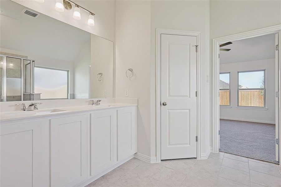 Bathroom with vanity, a shower with shower door, and tile patterned floors