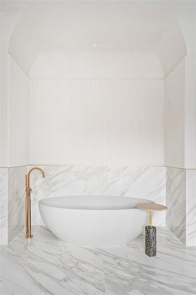 The oversized soaking tub, imported from the Netherlands, sits below a unique plastered cove ceiling, featuring top-of-the-line plumbing fixtures. This exquisite setup offers a luxurious and serene bathing experience.