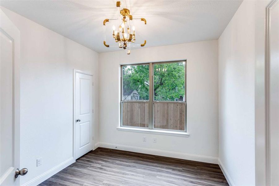 Spare room with a notable chandelier and hardwood / wood-style floors