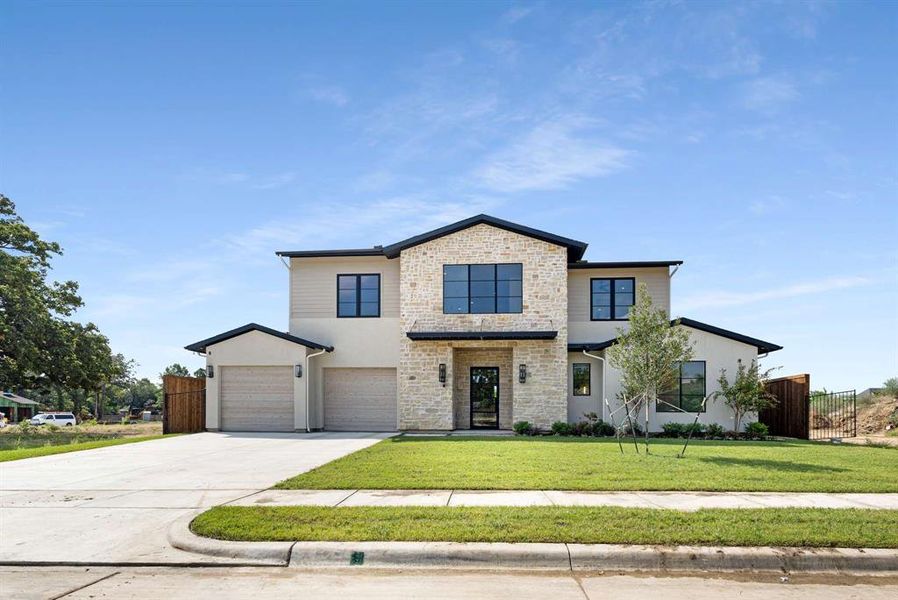 View of front of property featuring a garage and a front lawn