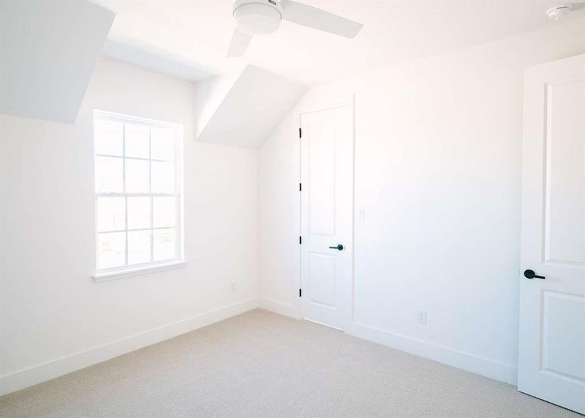 Bonus room with vaulted ceiling, ceiling fan, and light colored carpet