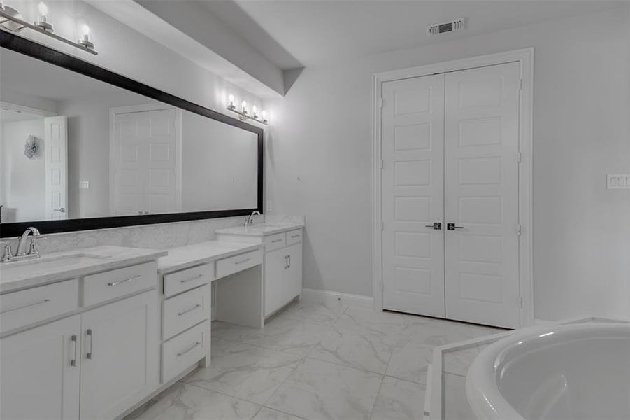 Bathroom featuring tile floors, a tub, double sink, and oversized vanity
