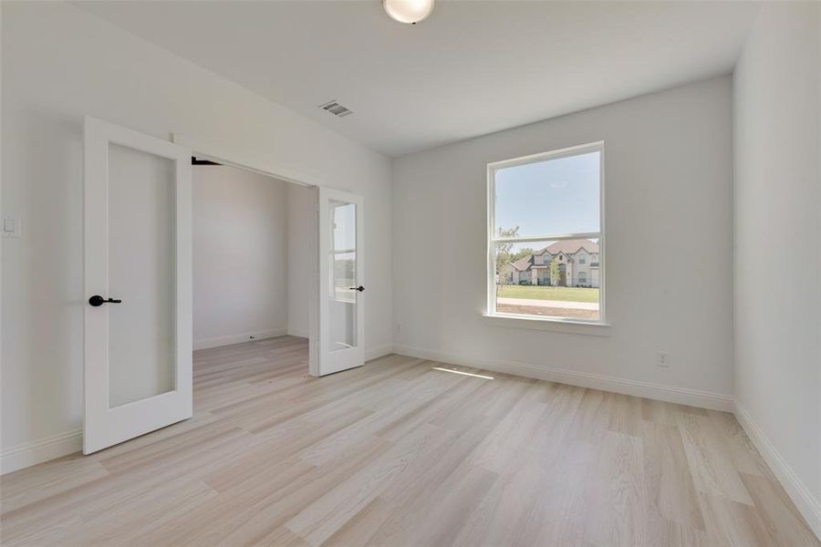 Unfurnished bedroom with french doors and light hardwood / wood-style flooring