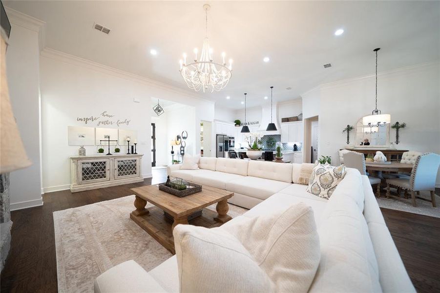 Living room featuring crown molding, dark wood-type flooring, and a chandelier