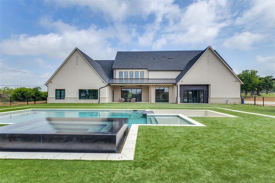 Back of house featuring a pool with hot tub and a lawn