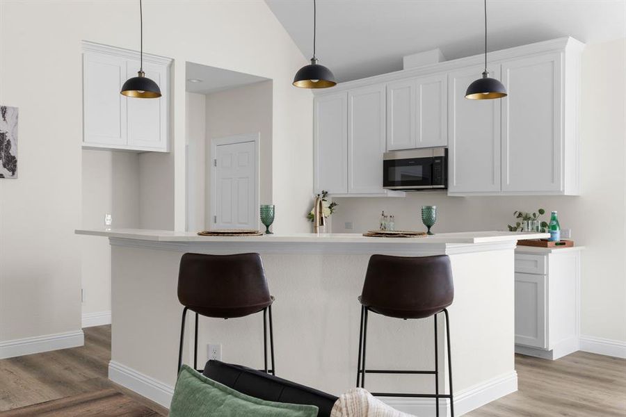 Kitchen featuring a center island with sink, vaulted ceiling, white cabinetry, and light hardwood / wood-style floors