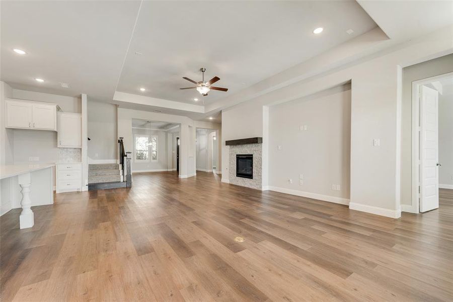 Living room featuring light hardwood / wood-style flooring, a tray ceiling, and ceiling fan