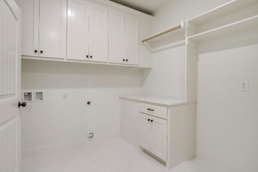 Laundry area with light tile patterned floors, gas dryer hookup, electric dryer hookup, washer hookup, and cabinets