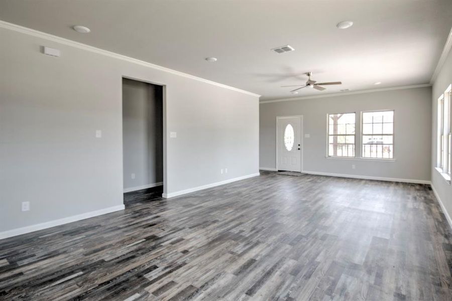 Spare room featuring crown molding, dark wood-type flooring, and ceiling fan