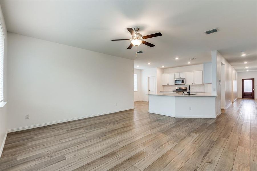 Unfurnished living room featuring ceiling fan and light hardwood / wood-style flooring