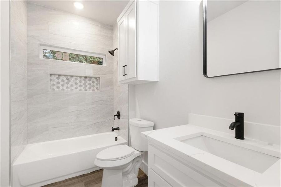 Full bathroom with vanity, toilet, hardwood / wood-style floors, and tiled shower / bath