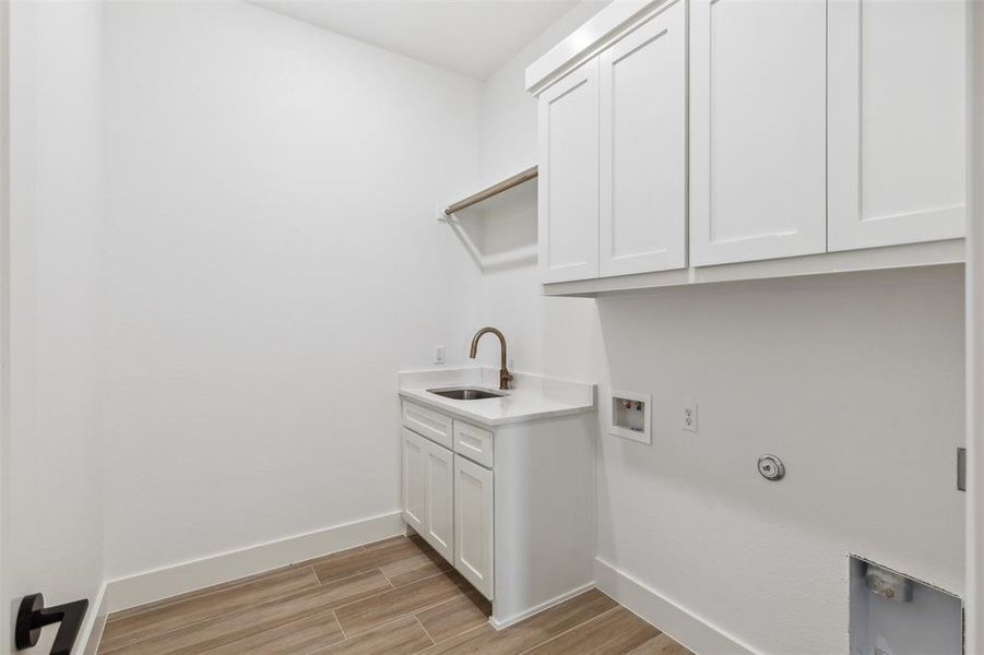 Laundry room with cabinets, hookup for a washing machine, light hardwood / wood-style flooring, and sink