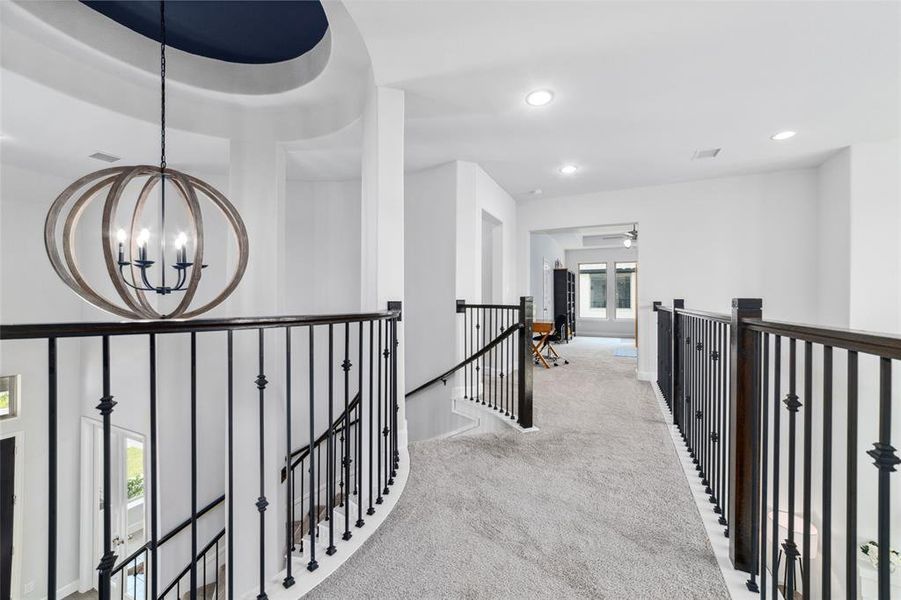 This spacious open-concept upper hallway featuring and elegant wrought iron railing.