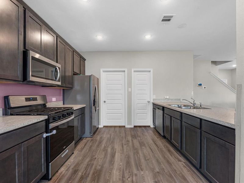 This beautiful kitchen features ample countertop space, dark stained cabinets, a large sink overlooking your family room, and recessed lighting.