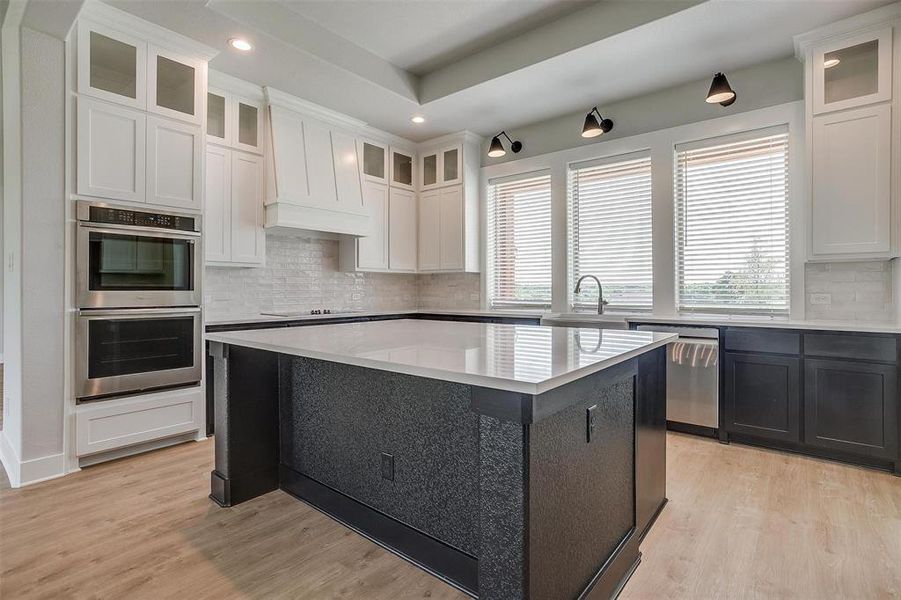 Kitchen featuring appliances with stainless steel finishes, light wood-type flooring, and tasteful backsplash
