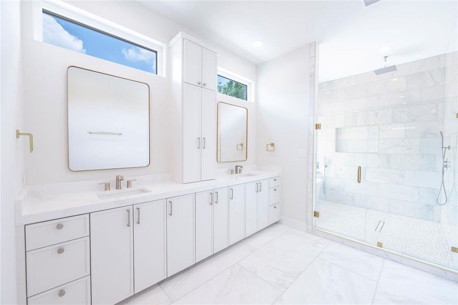 Bathroom featuring a shower with shower door, dual vanity, and tile flooring