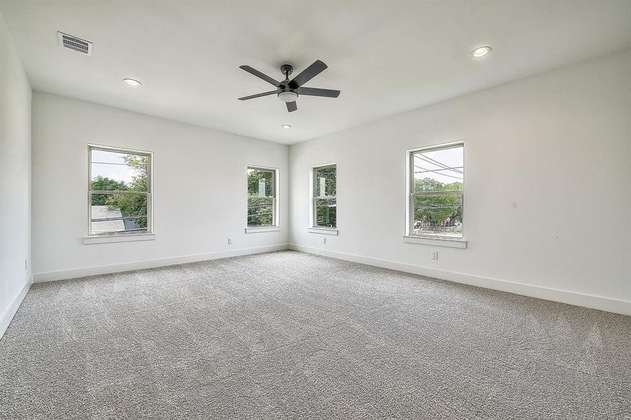 Carpeted spare room with ceiling fan and a wealth of natural light