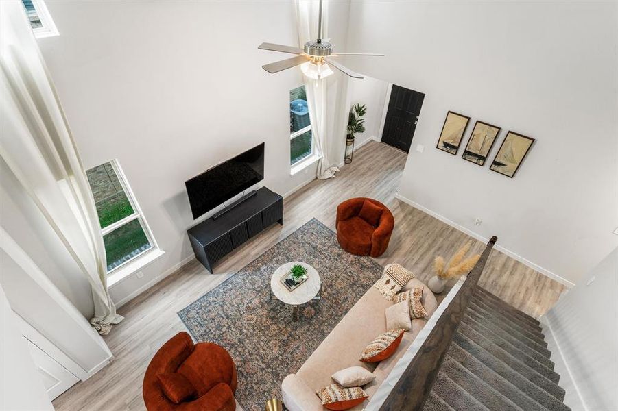 Living room featuring ceiling fan, a towering ceiling, and light wood-type flooring