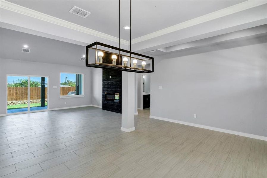 Unfurnished dining area with a notable chandelier, a multi sided fireplace, ornamental molding, and light hardwood / wood-style flooring