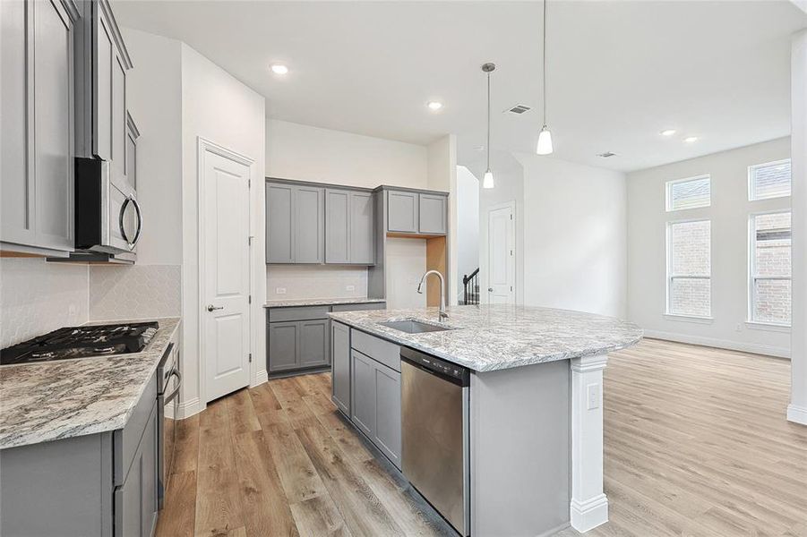 Kitchen with appliances with stainless steel finishes, a kitchen island with sink, light wood-type flooring, gray cabinetry, and sink