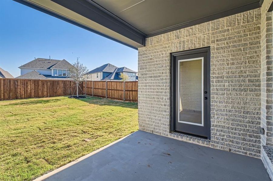 Doorway to property featuring a patio and a lawn