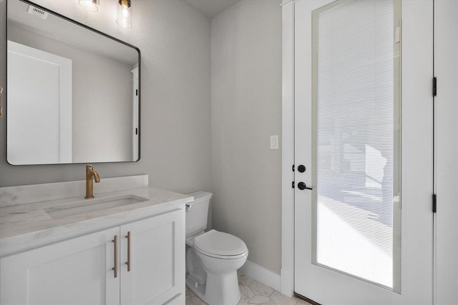 Half bath off of gameroom with a door that leads to the patio. Perfect bathroom for a entertaining and potential future pool!