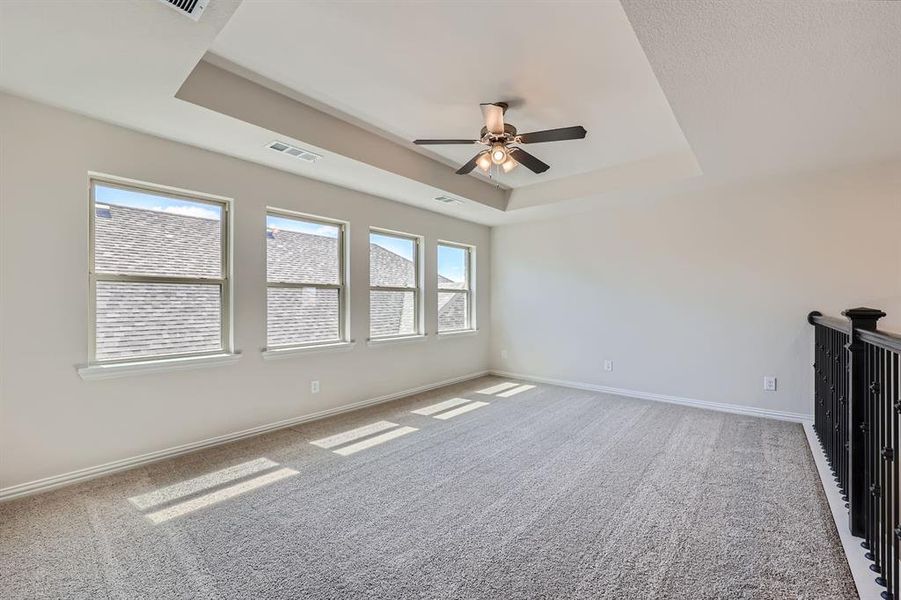 Living room with ceiling fan, carpet floors, and a raised ceiling