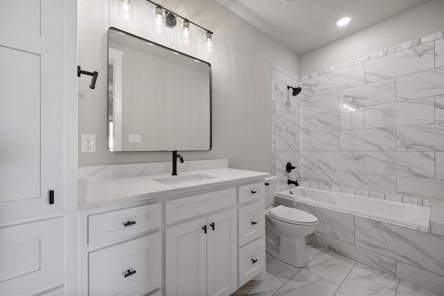 Full en-suite guest bathroom with vanity, toilet, and tiled shower / bath combo