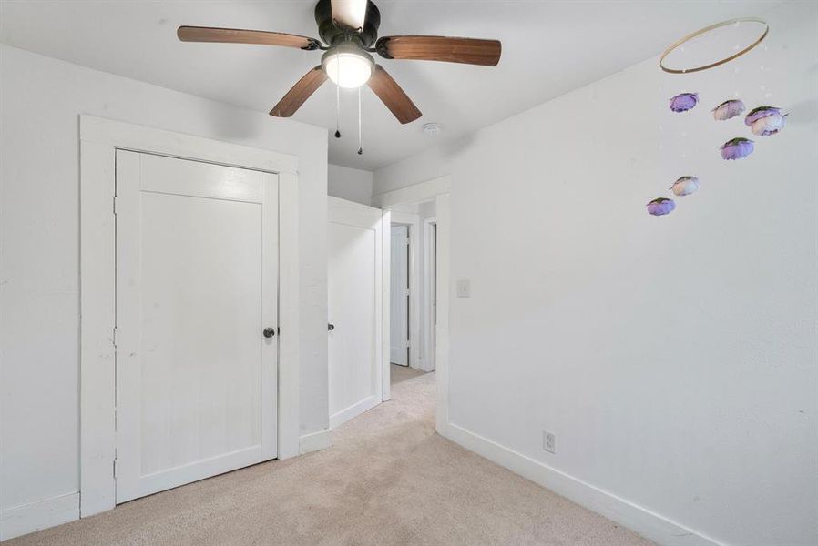 Unfurnished bedroom featuring ceiling fan, light colored carpet, and a closet