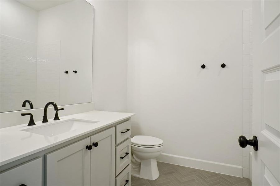 Bathroom with vanity, parquet floors, and toilet