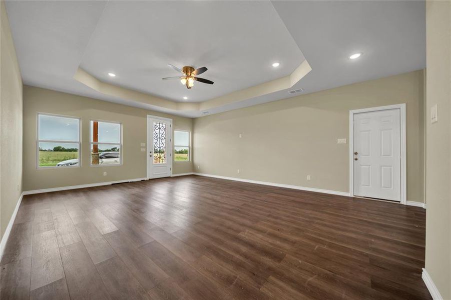 Unfurnished room featuring a healthy amount of sunlight, dark hardwood / wood-style flooring, and a tray ceiling