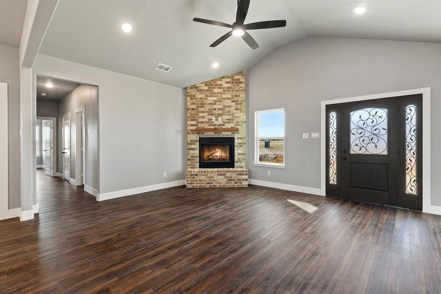 Unfurnished living room with ceiling fan, high vaulted ceiling, dark hardwood / wood-style floors, and a brick fireplace