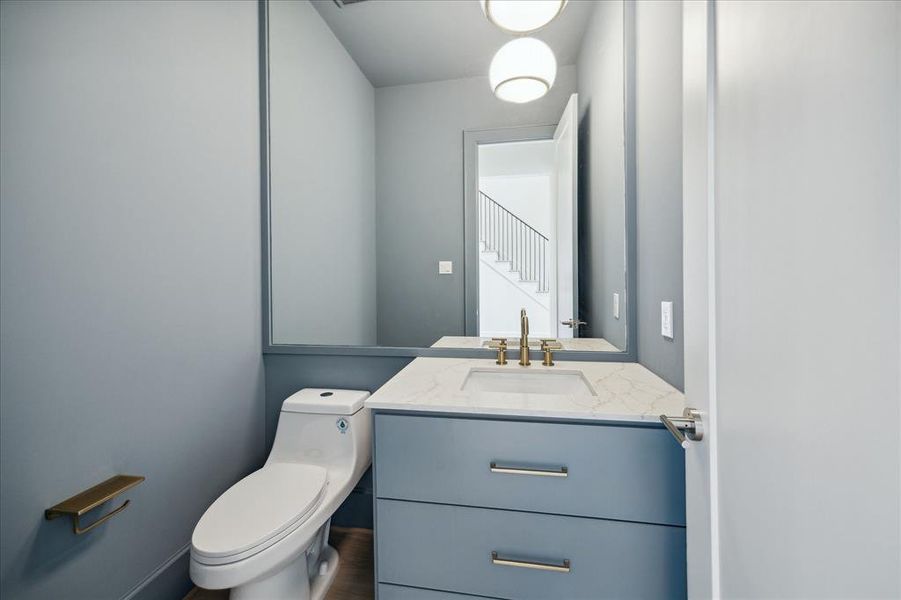 The designer guest bath just off the foyer is lux with brass fixtures, rich paint color and decorative lighting.