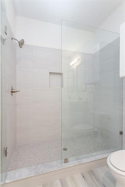 Bathroom featuring a shower with shower door and toilet