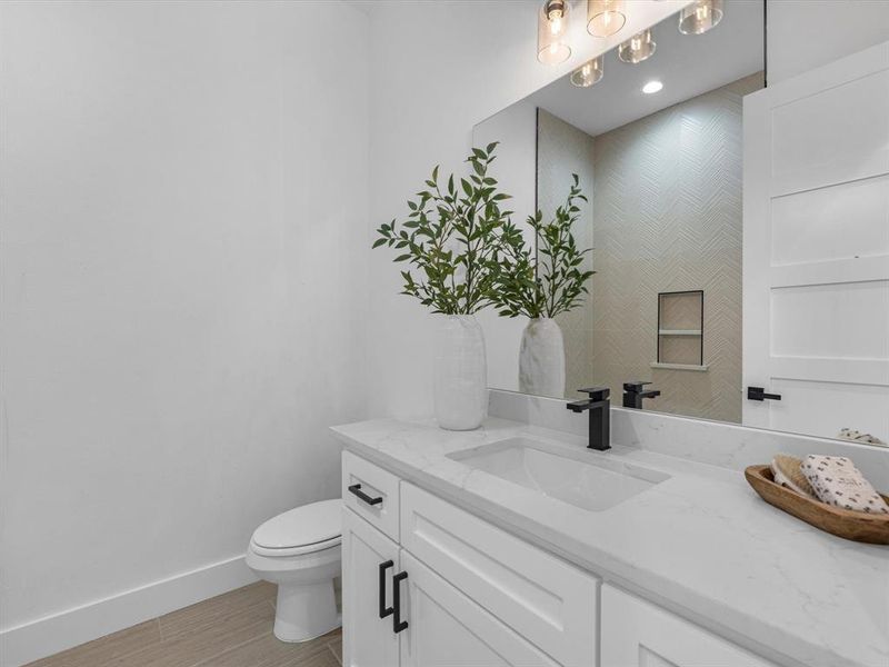 The guest bathroom is spacious, offering tons of counter space,  a tub/shower combo adorned with tile finishing that extends all the way to the ceiling, complemented by black hardware.