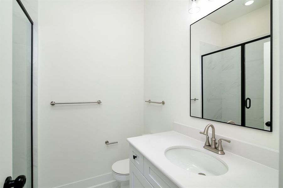 Bathroom featuring walk in shower, vanity, and toilet