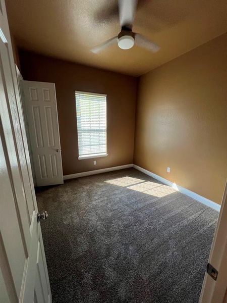 Carpeted empty room with ceiling fan and a textured ceiling